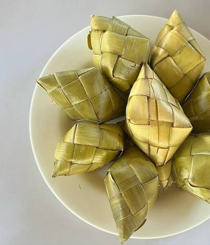 Woven coconut leaf pouches containing cooked puso hanging rice